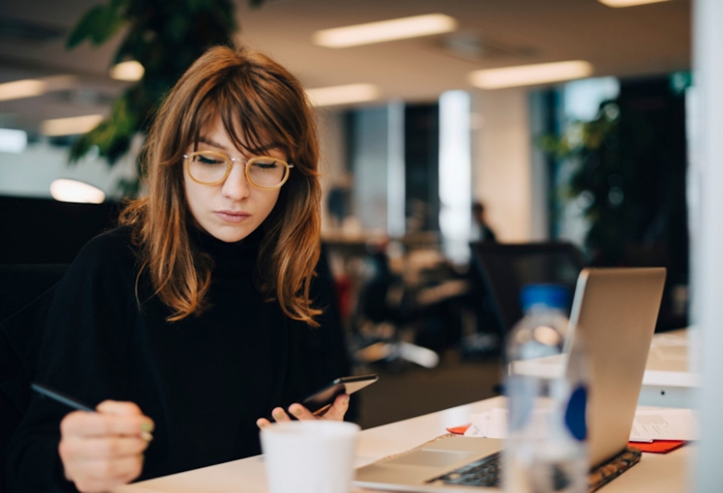 Women sitting at desk haling phone and taking notes