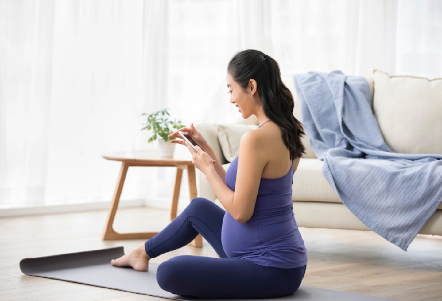 A pregnant woman sitting on a yoga mat